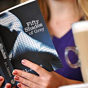 A woman reads E L James 50 Shades of Grey in public